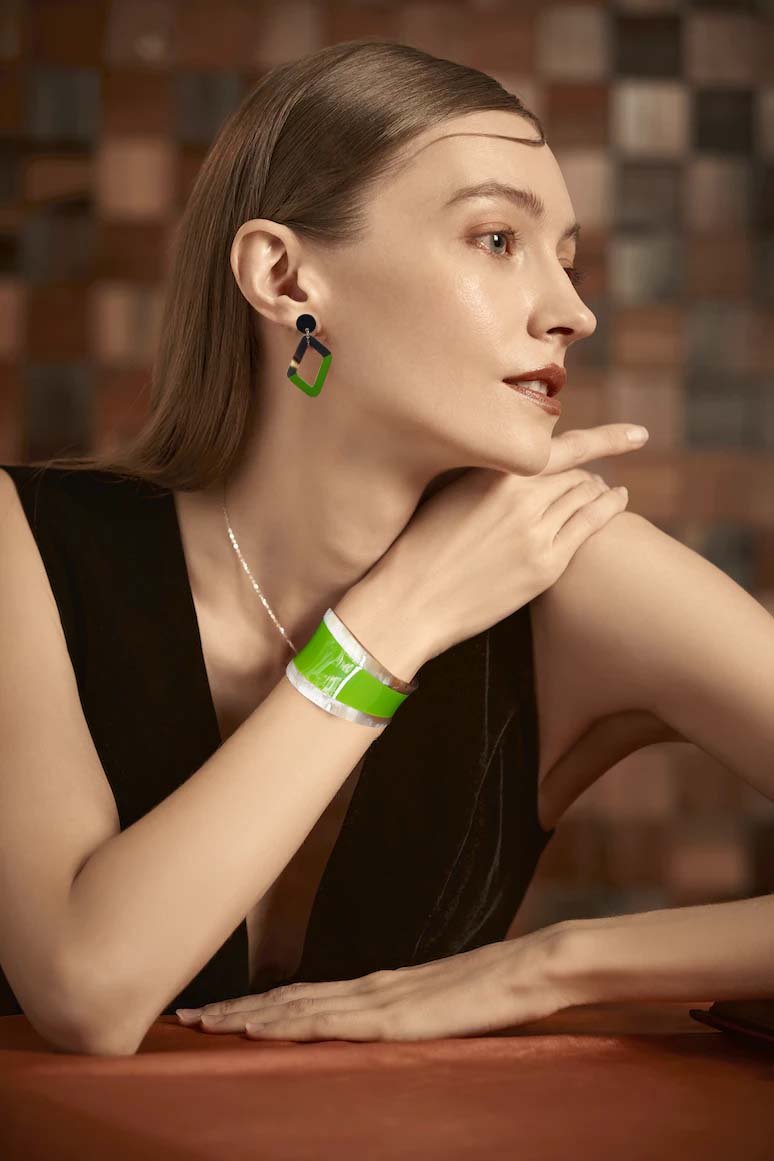 a model is wearing green horn cuff bracelet and rhombus earrings