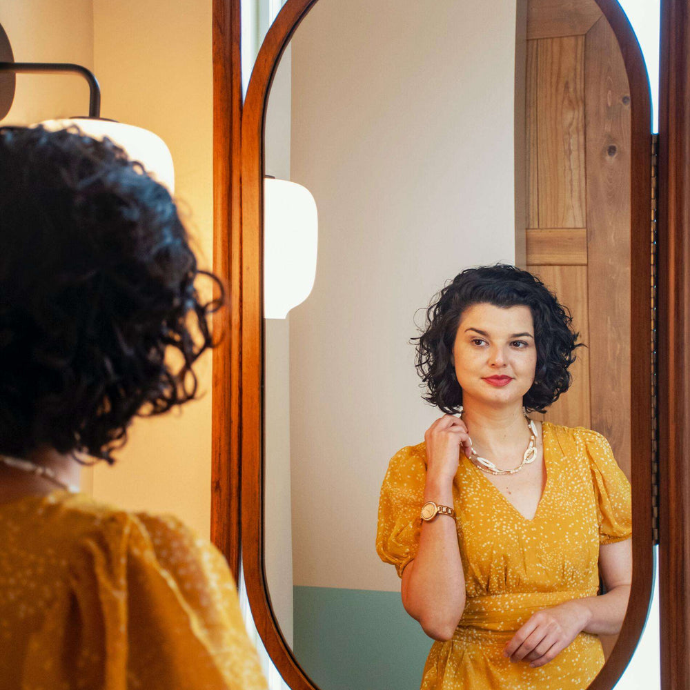 a girl wears hypoallergenic earrings in front of mirror