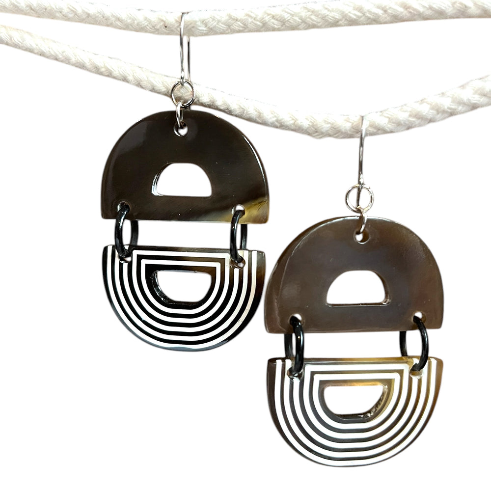
                  
                    Artisan buffalo horn hook earrings in warm brown hues, designed with striking white lacquer patterns.
                  
                