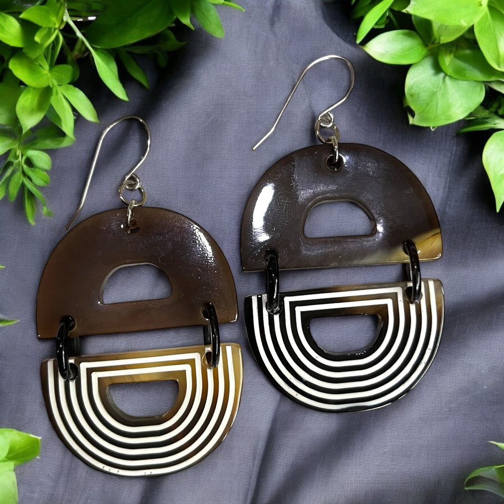 
                  
                    Handmade D-shaped dangle earrings feature brown and white color in the natural light
                  
                