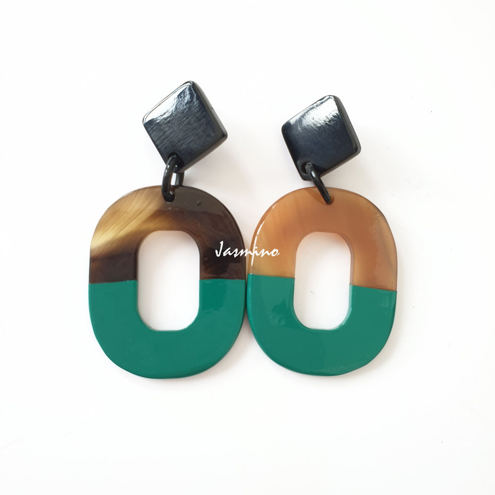 
                  
                    Handmade oval drop earrings feature deep emerald and amber color with natural buffalo horn material in the natural light
                  
                