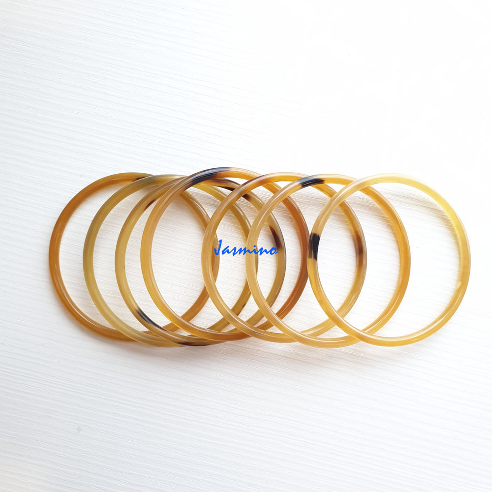 
                  
                    set of seven circle honey buffalo horn bracelets on a light background, an impressive gift for her
                  
                