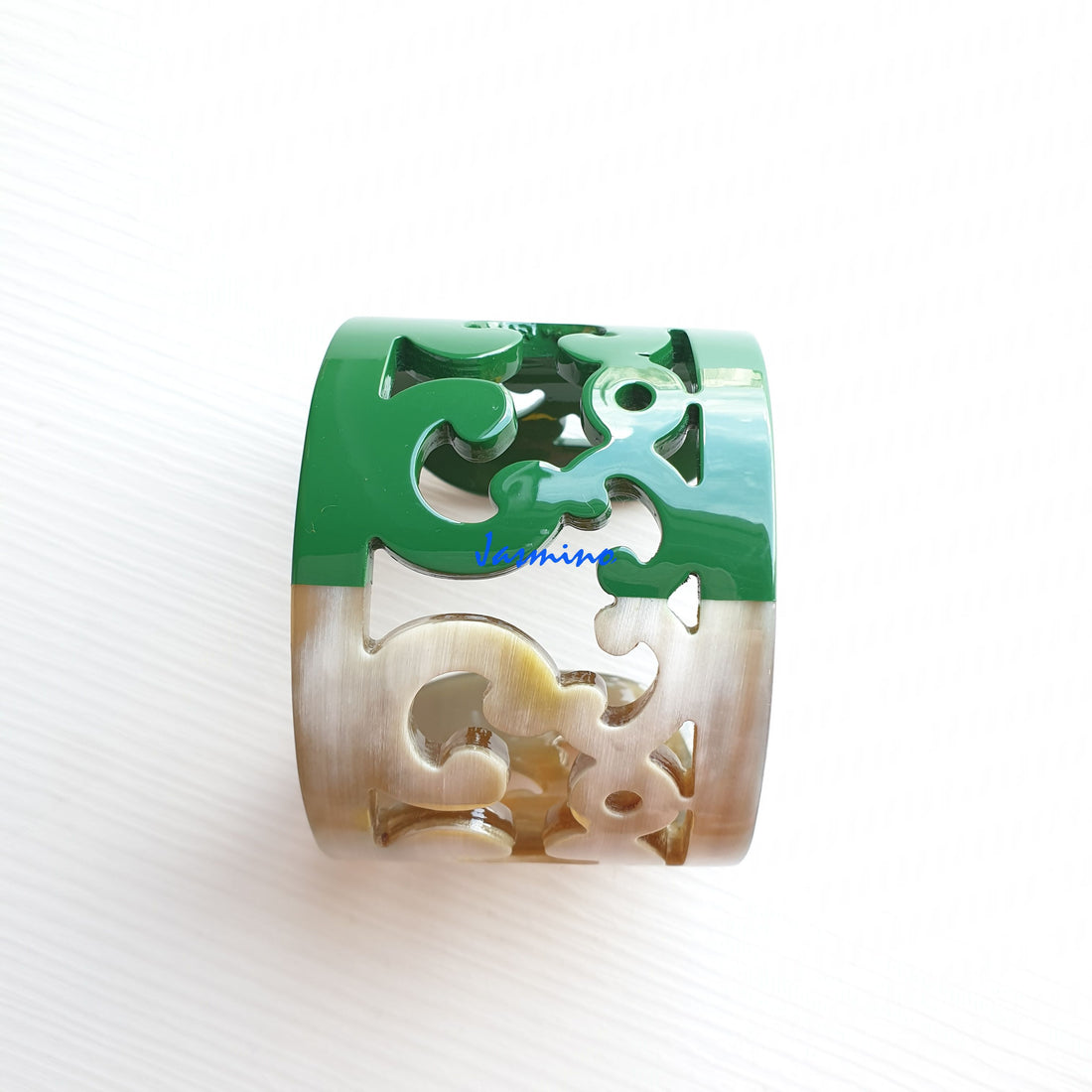 A handmade cuff bracelet is designed exquisitely with a green color on a white background 