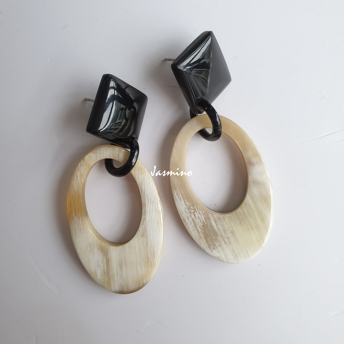 Handmade oval earrings feature white color and natural buffalo horn in the natural light