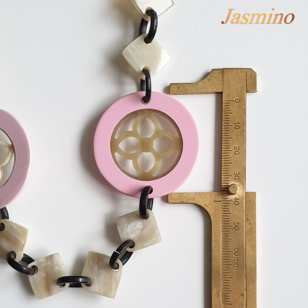 This necklace is made of natural lozenge buffalo horn pieces and four circle pink horn pieces with a unique pattern stands out on a light background, is a unique gift for friends