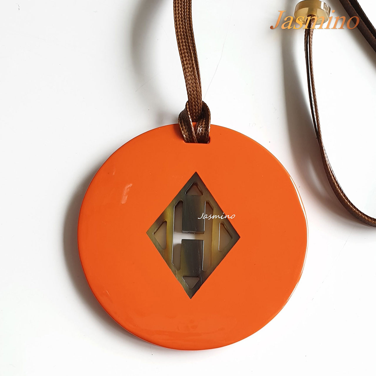 circular pendant with orange peel outside, inside with lozenge pattern made from natural buffalo horn on a light background, an impressive gift for her