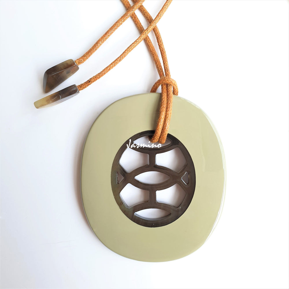 
                  
                    A model is wearing unique handmade Vintage oval pendant has a beige outline in natural buffalo horn for women in the natural light
                  
                