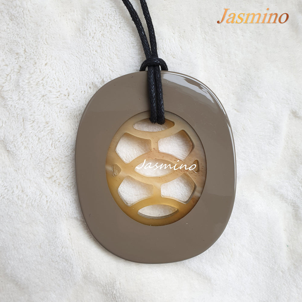 
                  
                    A model is wearing unique handmade Vintage oval pendant has a taupe outline in natural buffalo horn for women in the natural light
                  
                