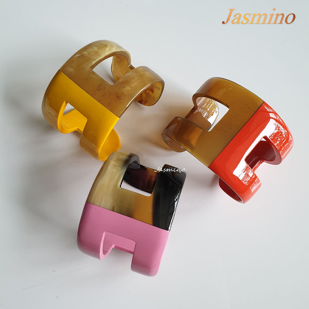 
                  
                    A set of three handmade cuff bracelets is shaped by "H" letter with natural buffalo horn material on a white background
                  
                