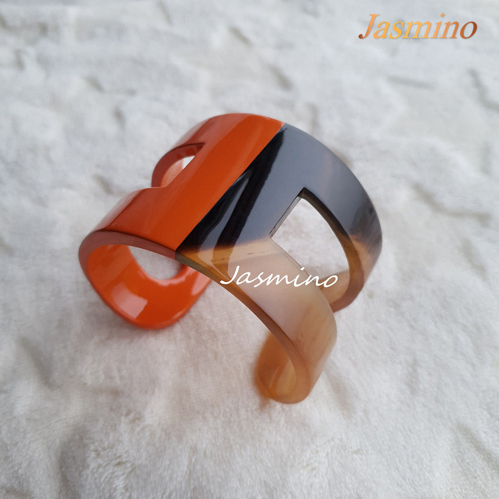 
                  
                    A cuff bracelet is designed with half natural buffalo horn and half  burnt orange lacquer in the natural light 
                  
                