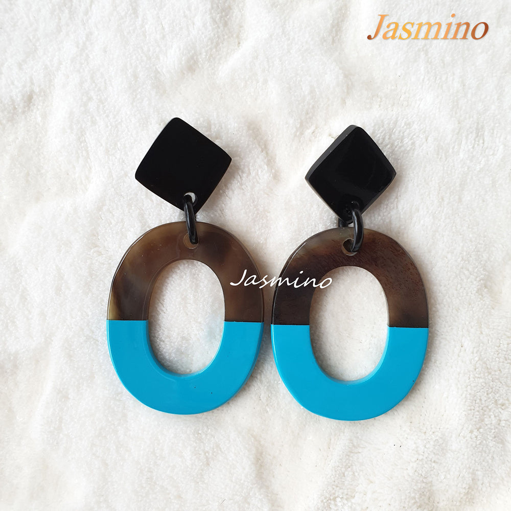 
                  
                    Handmade oval earrings are covered by a brown and sky blue color for a unique gift on a white background
                  
                