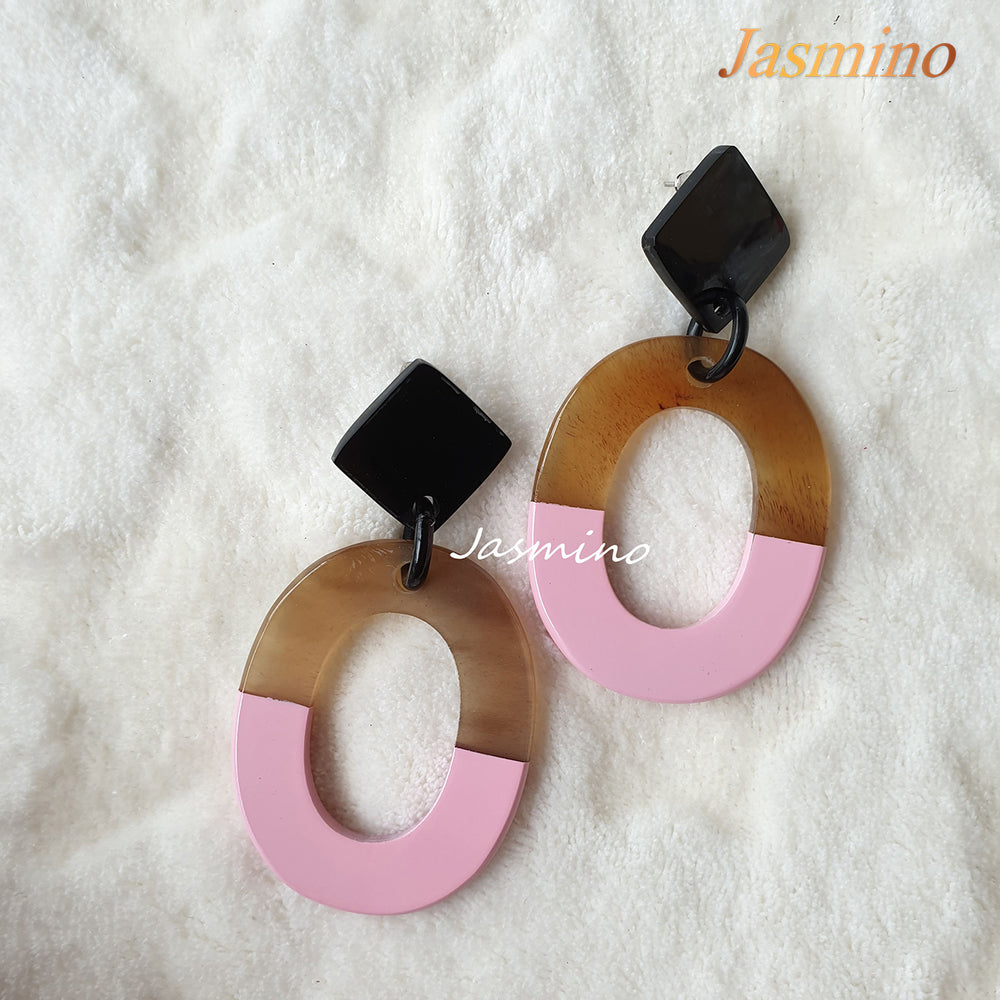 
                  
                    Handmade oval earrings are covered by a brown and pink color for a unique gift on a white background
                  
                