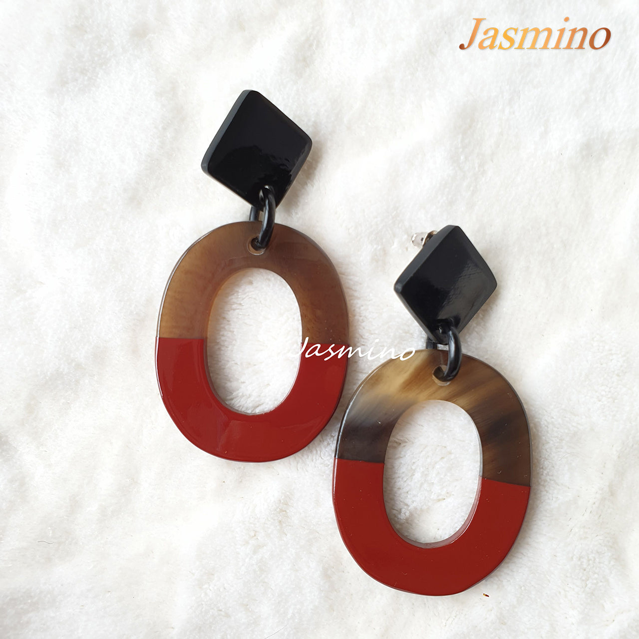Handmade oval earrings are covered by a brown and red color for a unique gift on a white background for Christmas