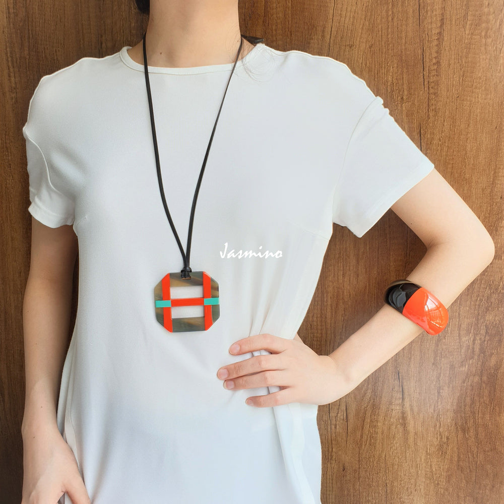 
                  
                    A model is wearing orange lacquer pendant on the light background, impressive gift for her
                  
                