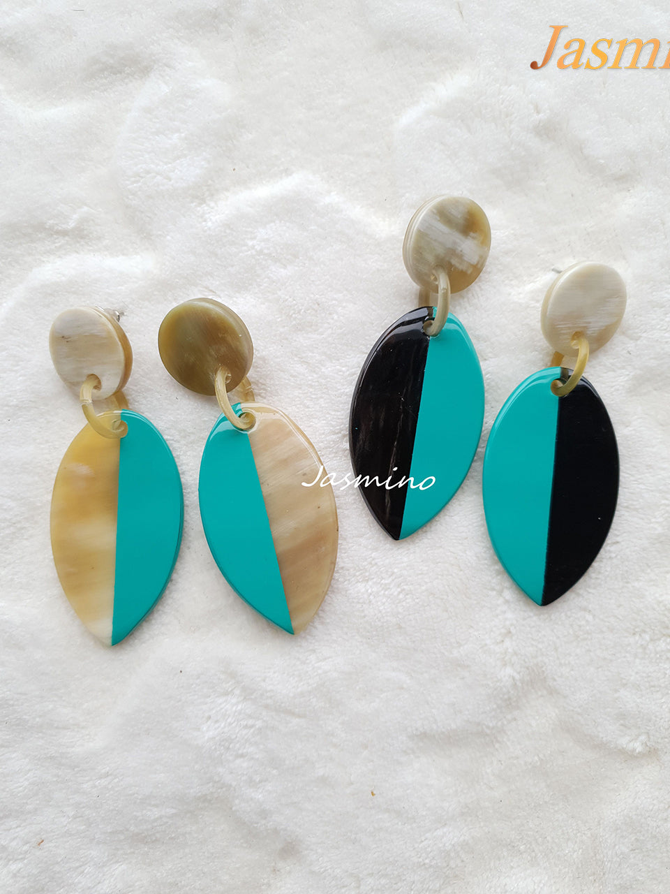 Two couples of earrings are shaped by a leaf with a black half and turquoise half