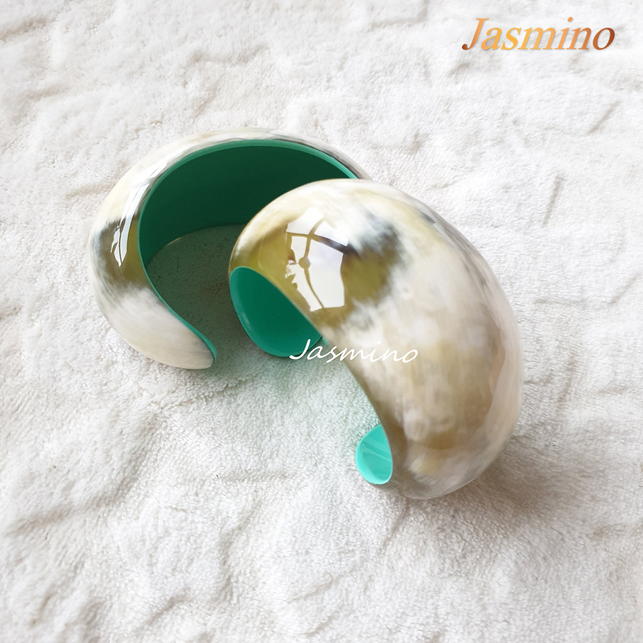 two Jasmino unique handmade cuff bracelets are shaped by a snail shell with a turquoise inside. It is made of natural buffalo horn for the best gifts