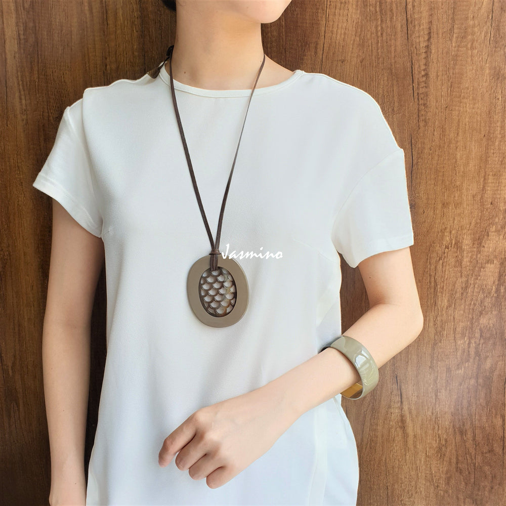 
                  
                    A model is wearing fish scale taupe pendant on the light background, impressive gift for her
                  
                