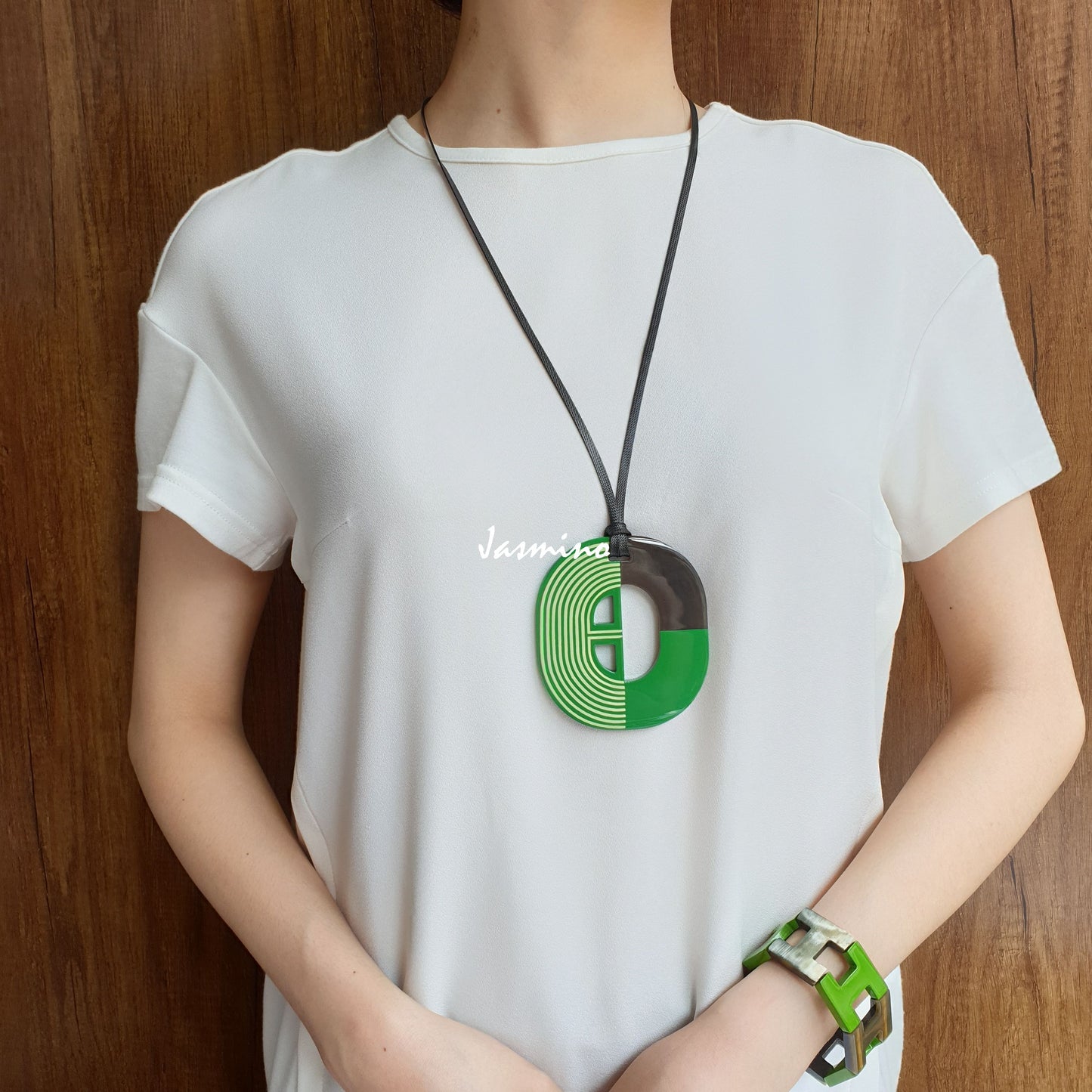 A women wears a green handmade necklace and geometric green bangle bracelet in the natural light