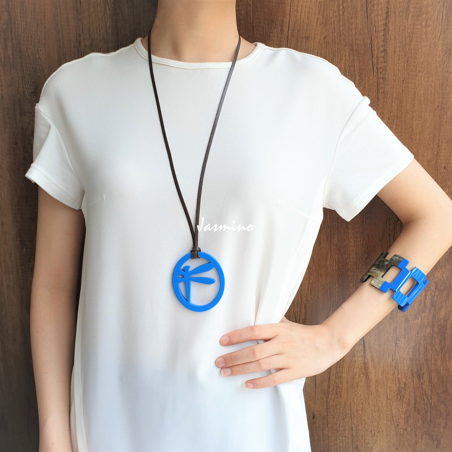 A model is wearing elliptical spring break pendant with dragonfly pattern inside on the light background, impressive gift for her