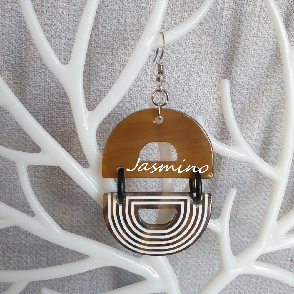 
                  
                    Handmade D-shaped dangle earrings feature brown and white color in the natural light
                  
                