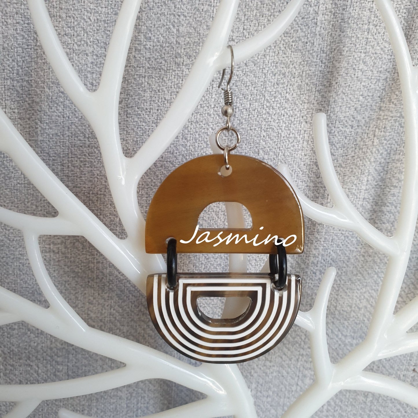Handmade D-shaped dangle earrings feature brown and white color in the natural light