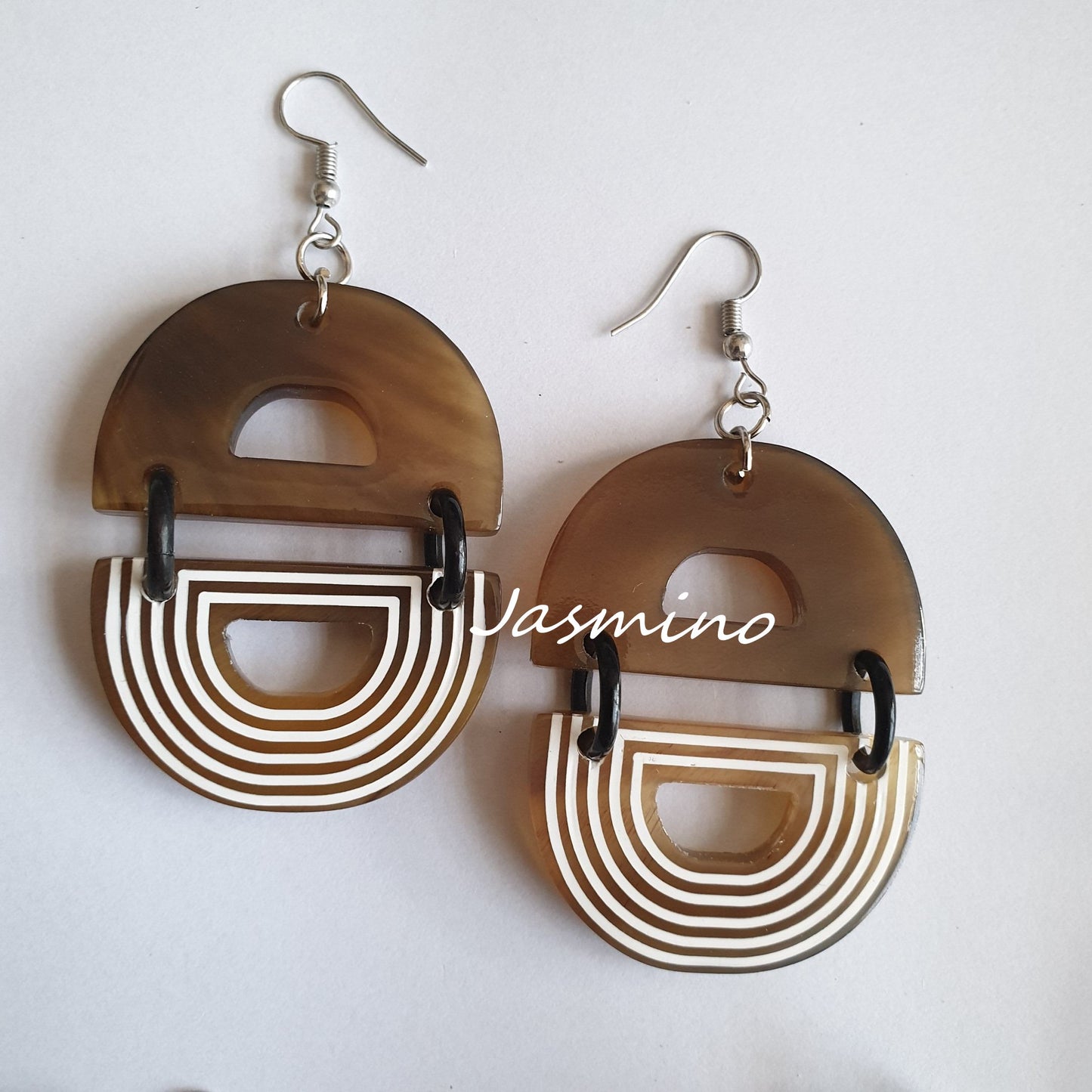 Handmade D-shaped dangle earrings feature brown and white color in the natural light