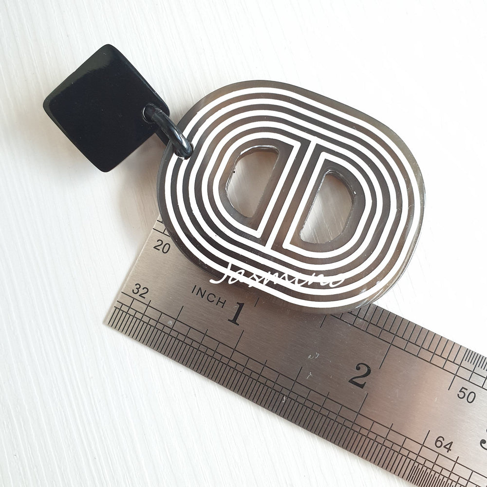 
                  
                    Handmade spiral double D-shaped oval earrings feature brown and white in the natural light
                  
                