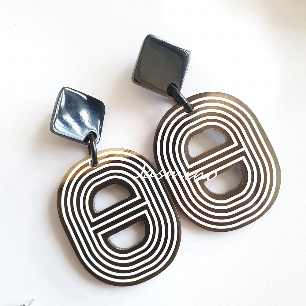 
                  
                    Handmade spiral double D-shaped oval earrings feature brown and white in the natural light
                  
                