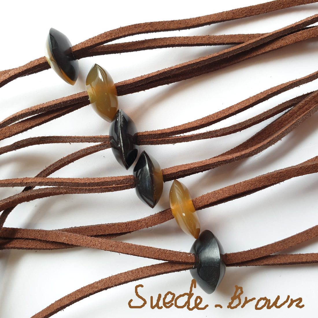 Suede-Brown cords with small natural buffalo horn pieces on the light background, impressive gift for her