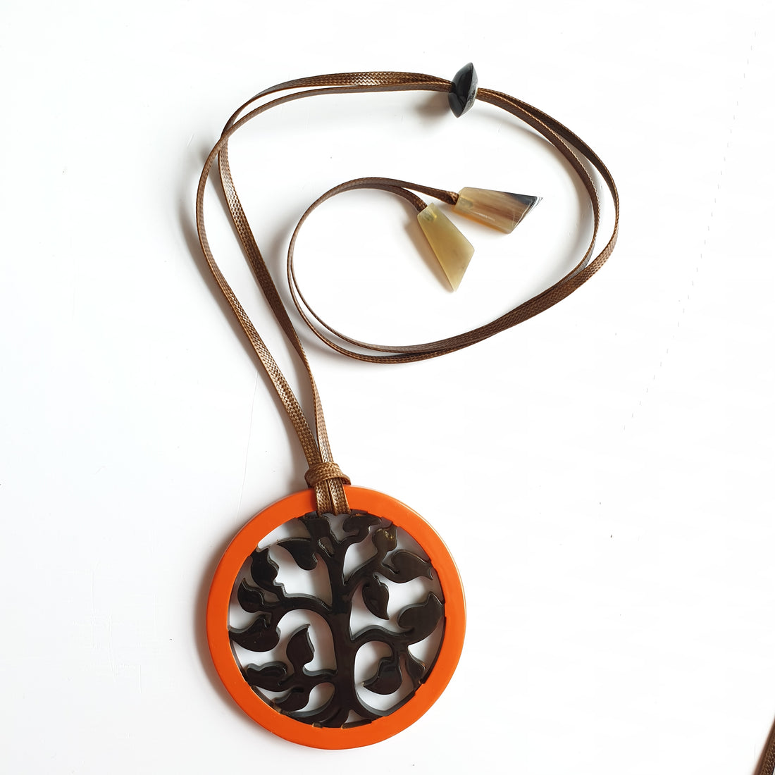 orange lacquer pendant with suede brown cord on the light background, impressive gift for her