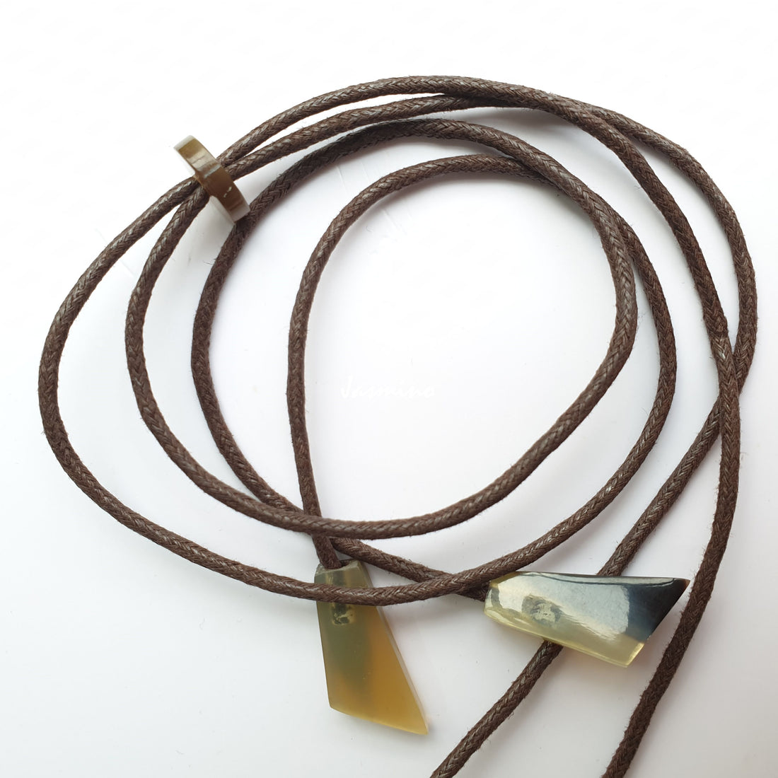 Suede-black cords with small natural buffalo horn pieces on the light background, impressive gift for her