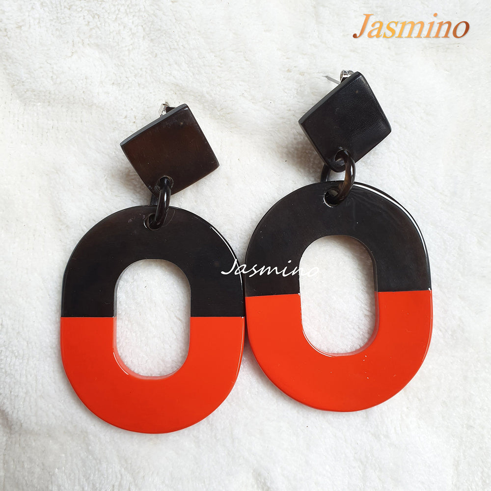 
                  
                    Handmade oval earrings feature light red with natural buffalo horn material in the natural light
                  
                