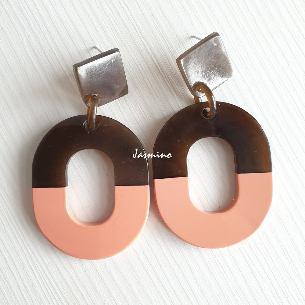 
                  
                    Handmade oval earrings feature coral pink with natural buffalo horn material in the natural light
                  
                