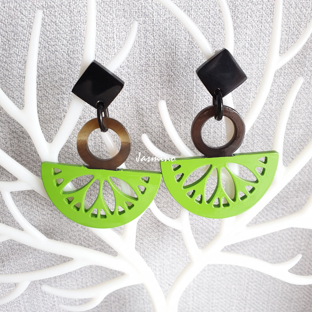 
                  
                    Handmade drop earrings are detailed by Kiwi fruit shape with bright green color and natural buffalo horn material on white faux branches
                  
                
