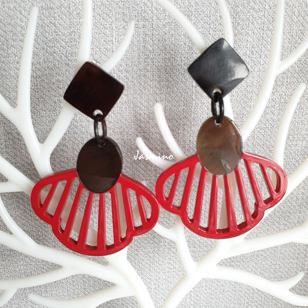 
                  
                    Handmade drop earrings are shaped by seashells with a red color in the natural light
                  
                