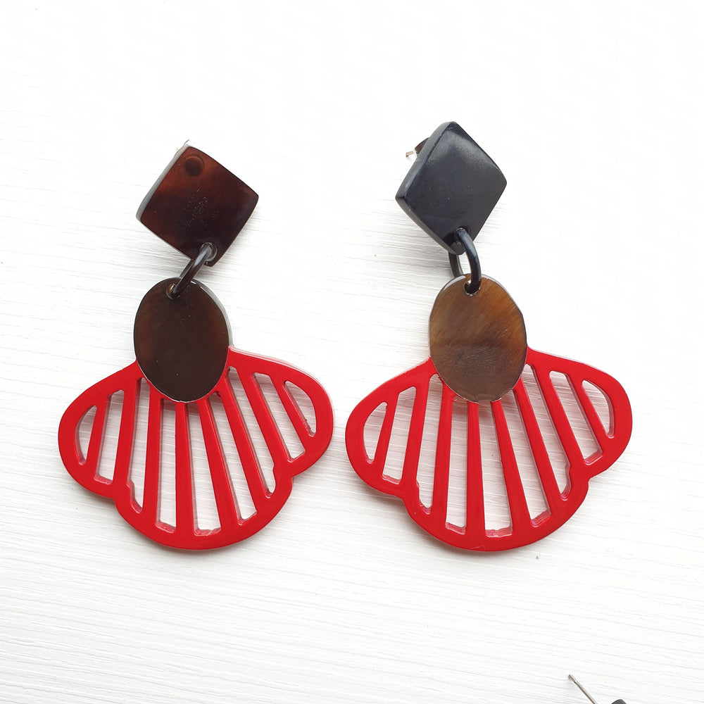 
                  
                    Handmade drop earrings are shaped by seashells with an orange color in the natural light
                  
                