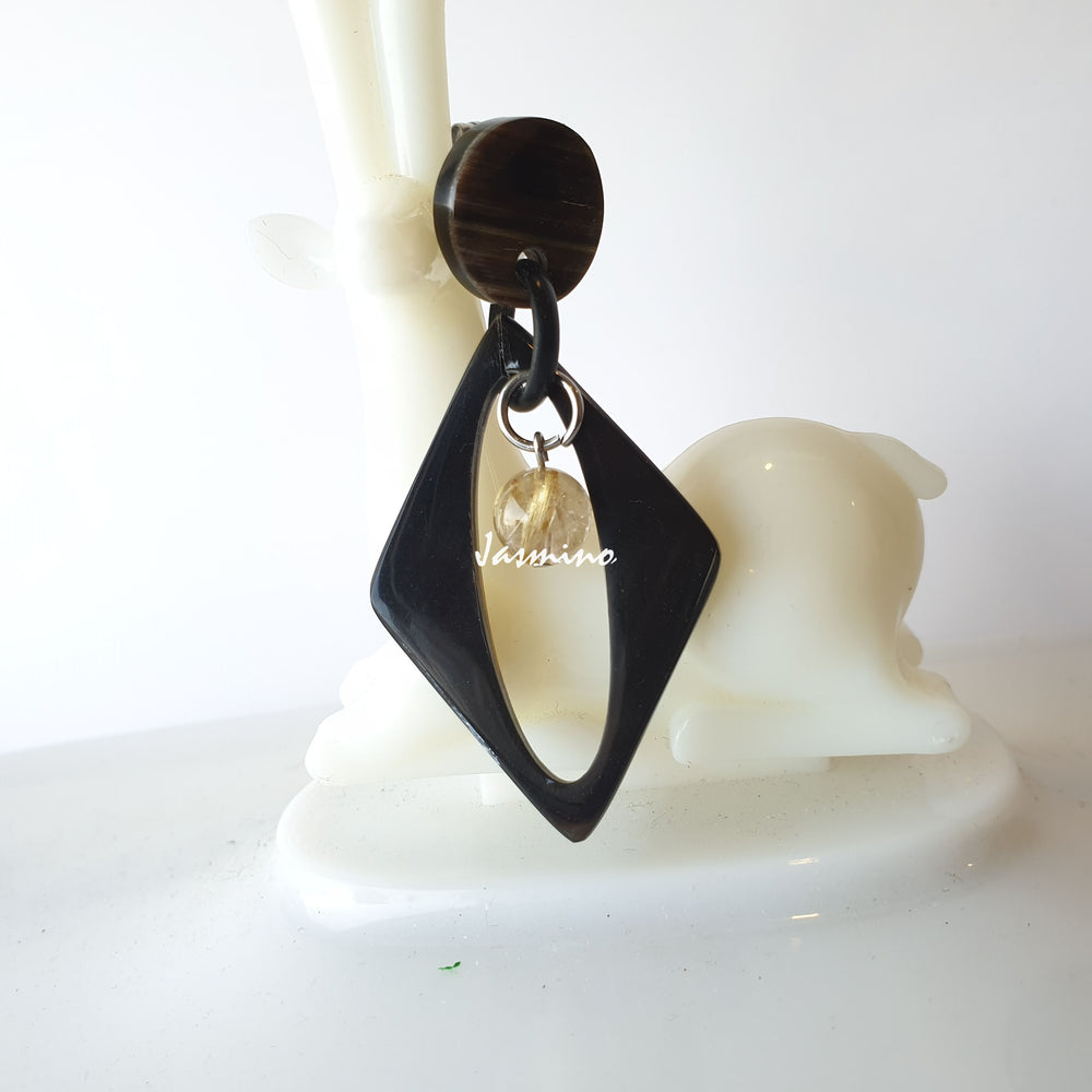 
                  
                    Handmade drop earrings feature a black oval and white pearl in the natural light
                  
                