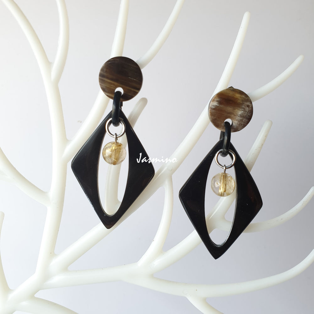 
                  
                    Handmade drop earrings feature a black oval and white pearl on white faux branches
                  
                