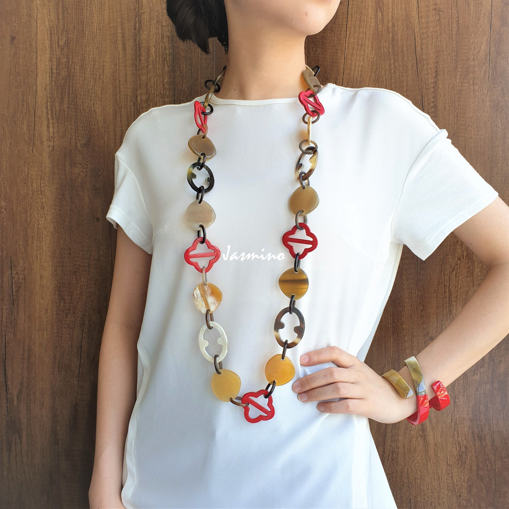 
                  
                    A model is wearing unique handmade red chain link necklace and cuff bracelet accessory in natural buffalo horn
                  
                