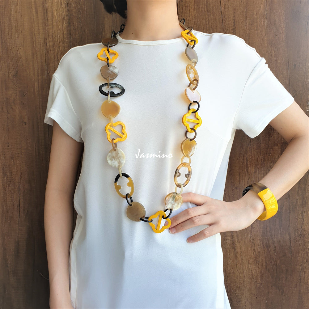 
                  
                    A model is wearing unique handmade yellow chain link necklace and cuff bracelet accessory in natural buffalo horn
                  
                