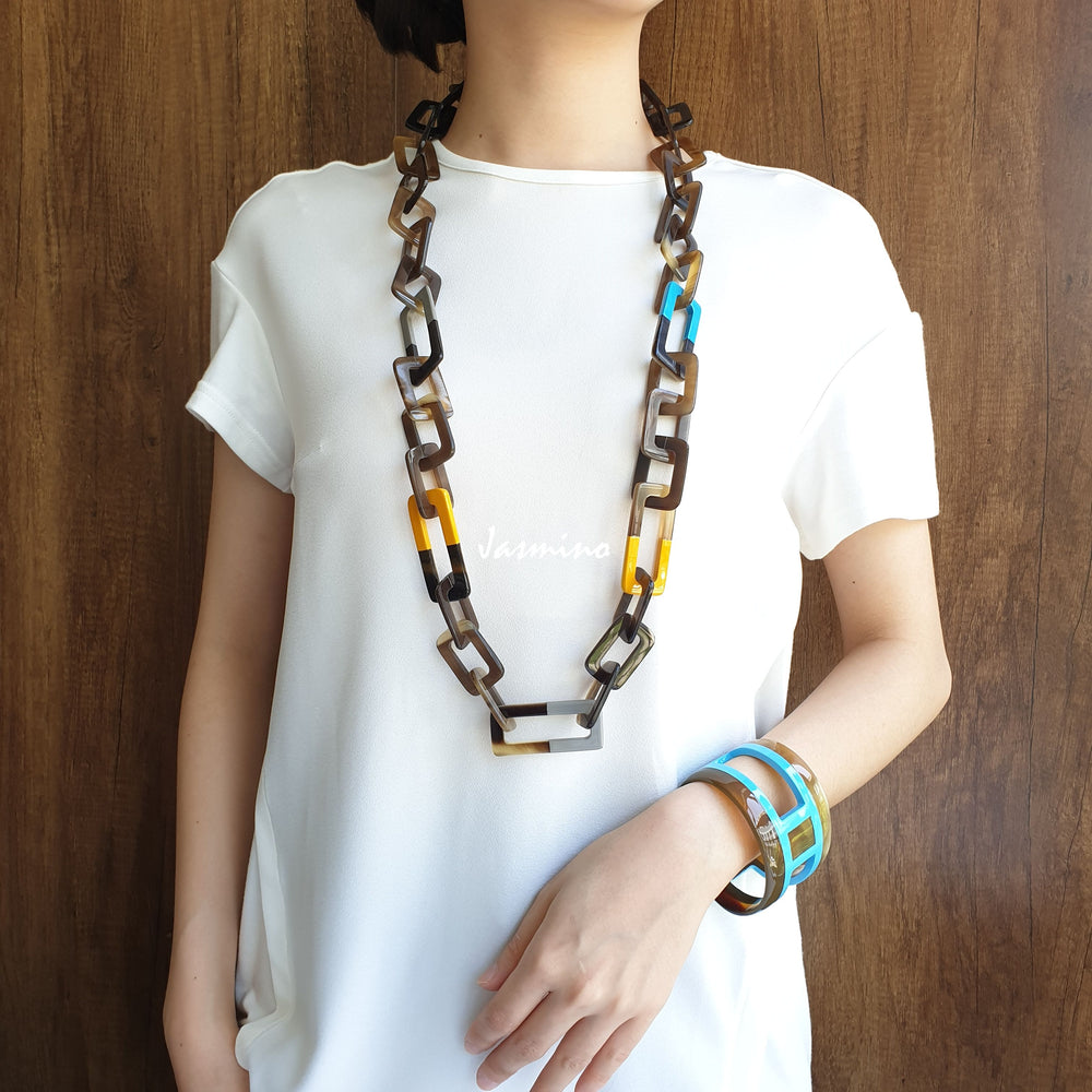 
                  
                    A model is wearing unique handmade Bohemian rectangle chain link necklace and cuff bracelet accessory in natural buffalo horn for women
                  
                