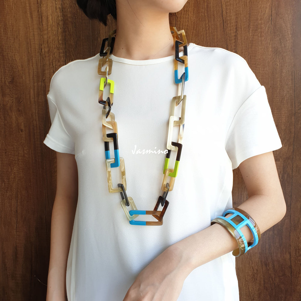 
                  
                    A model is wearing unique handmade Bohemian rectangle large chain link necklace and cuff bracelet featured blue and green in natural buffalo horn
                  
                