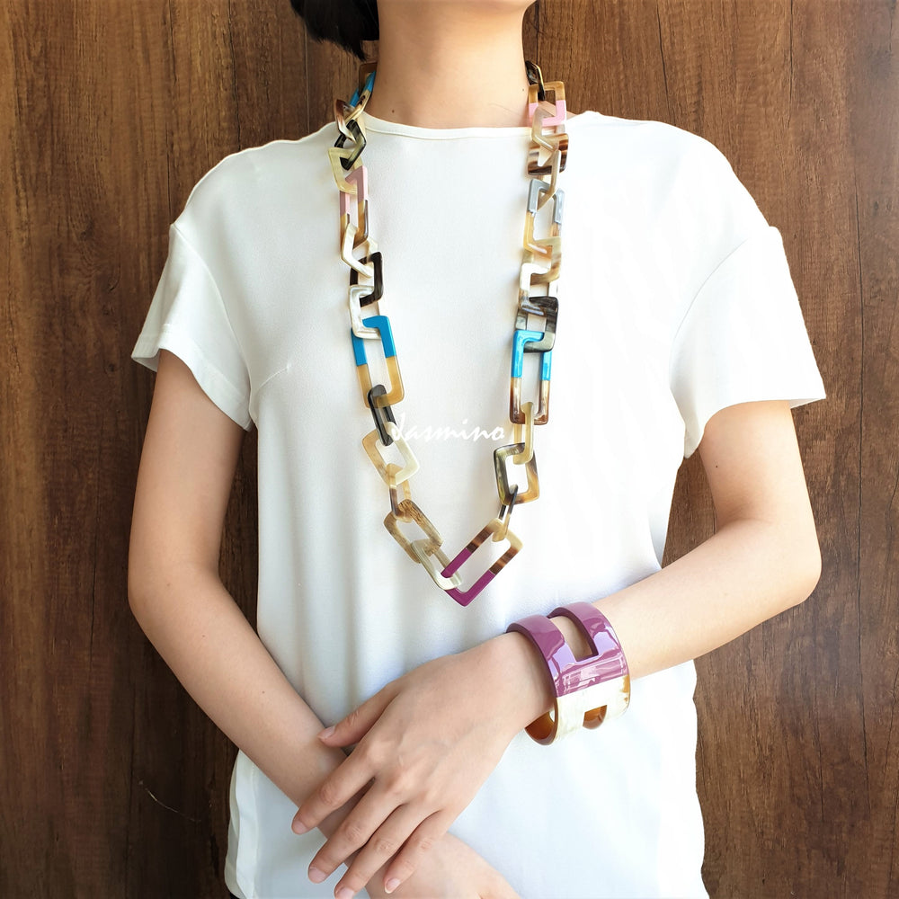 
                  
                    A model is wearing unique handmade Bohemian rectangle chain link necklace and cuff bracelet accessory featured purple and white in natural buffalo horn 
                  
                