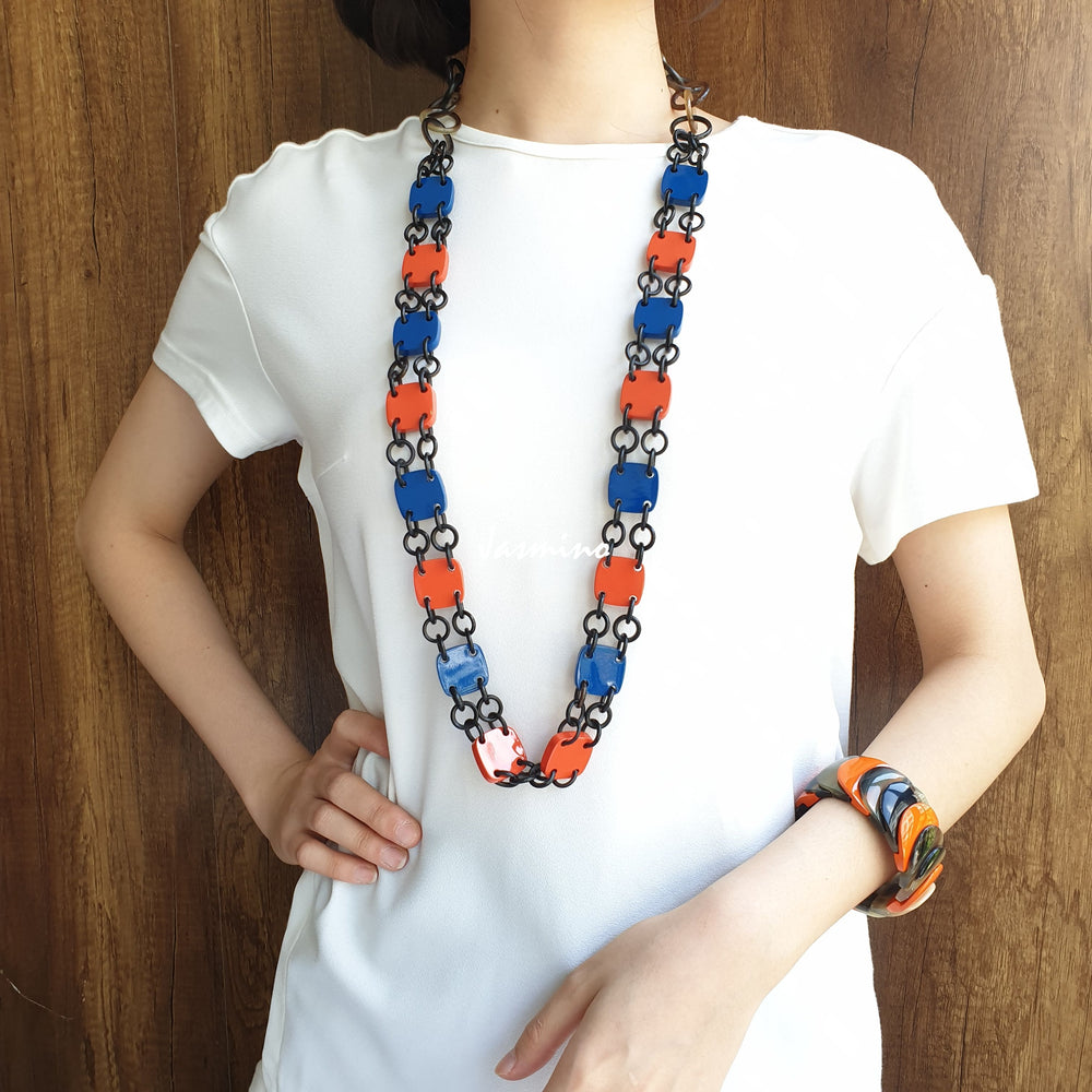 
                  
                    A model is wearing unique handmade Vintage alternating square chain link necklace and bangle bracelet accessory featured blue and orange in natural buffalo horn
                  
                