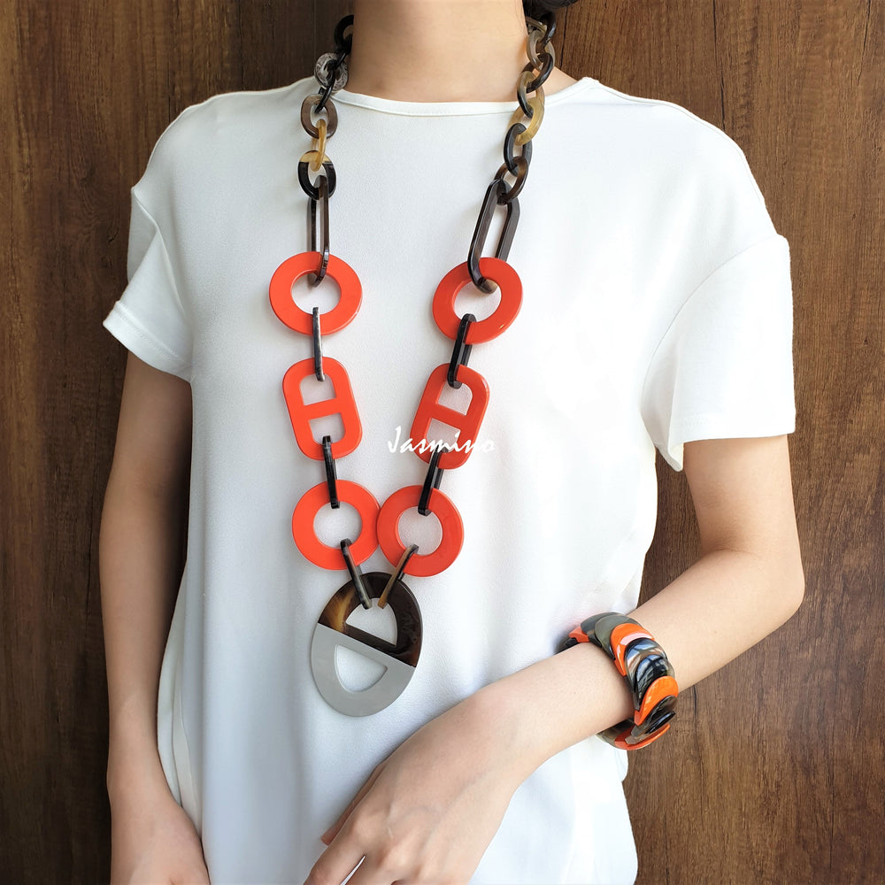 
                  
                    A model is wearing unique handmade chain link necklace and cuff bracelet featured grey and orange in natural buffalo horn
                  
                