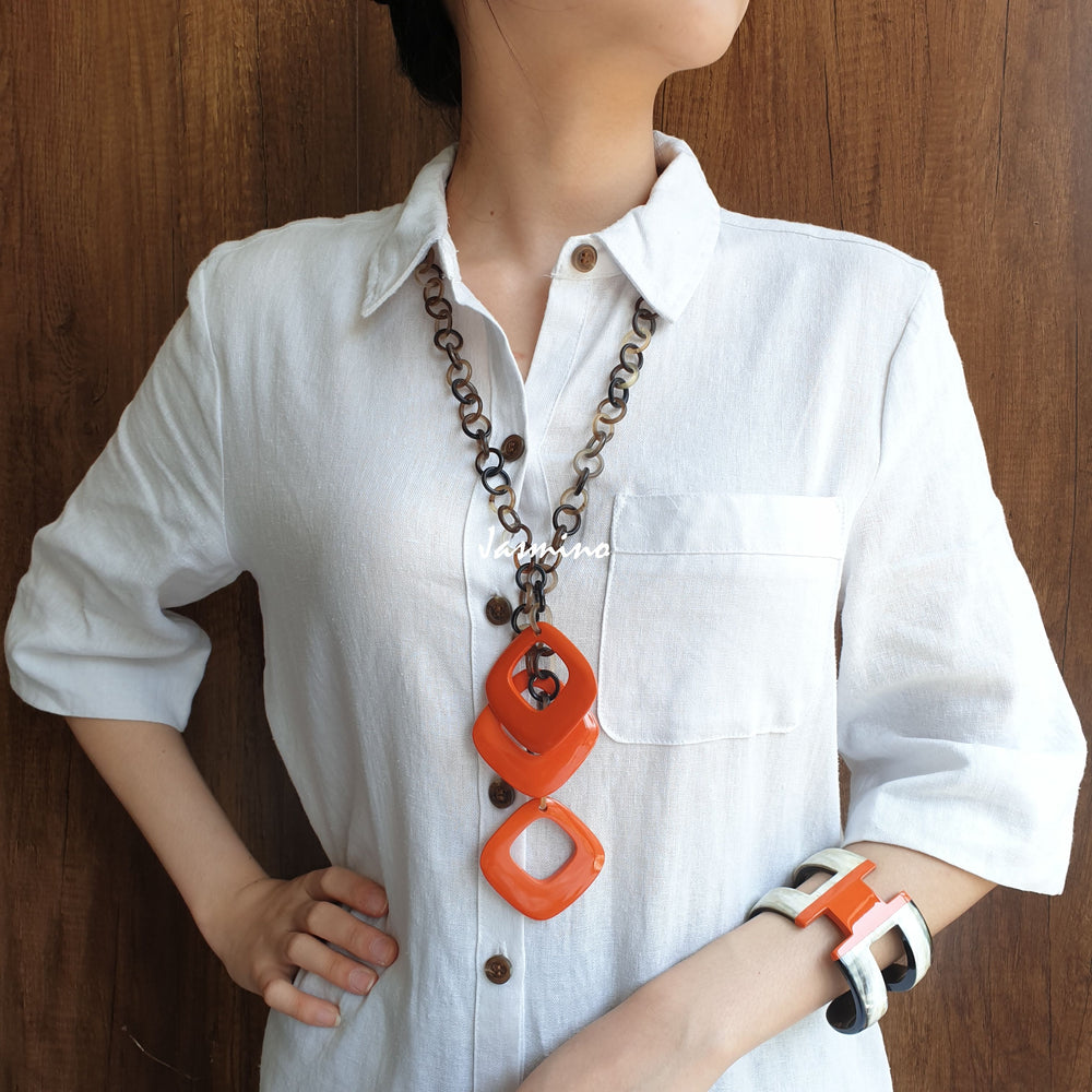 
                  
                    A model is wearing Jasmino unique handmade diamond shaped chain link necklace and H-shaped cuff bracelet in natural buffalo horn for women
                  
                