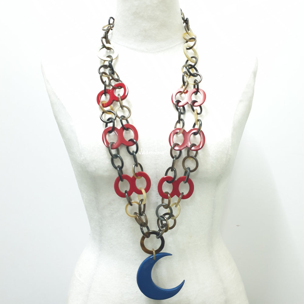 
                  
                    A model is wearing Jasmino unique handmade chain link necklace featured a blue crescent moon pendant jewelry accessory in natural buffalo horn for women
                  
                