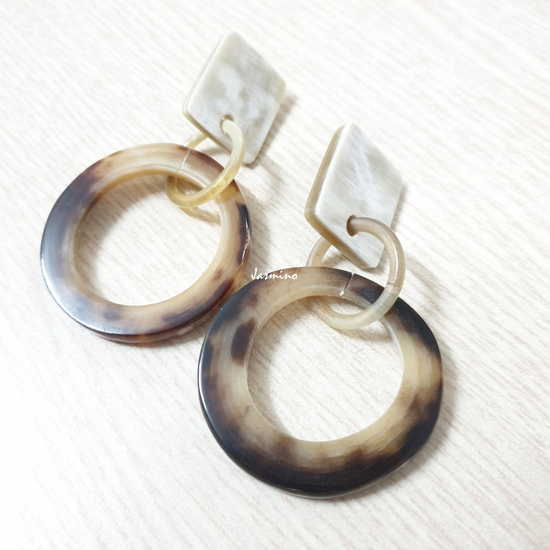 Handmade circular earrings feature leopard skin with brown and yellow in the natural light