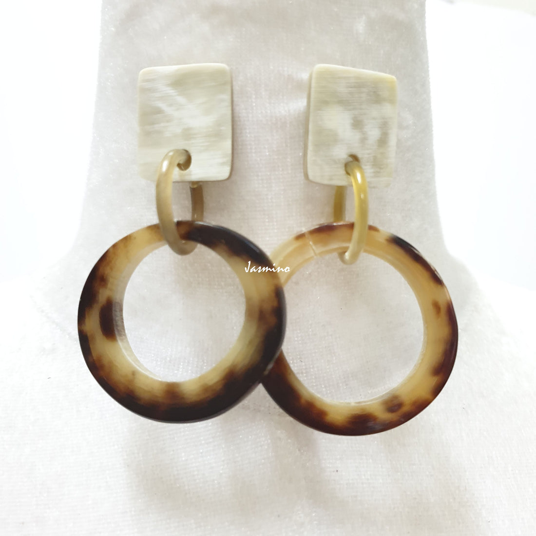 Handmade circular earrings feature leopard skin with brown and yellow in the natural light