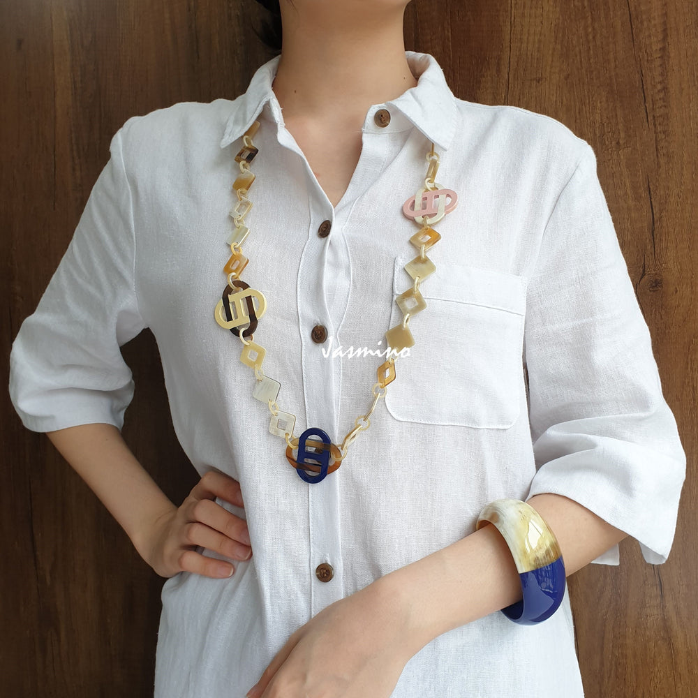 
                  
                    A model is wearing unique handmade chain link necklace and cuff bracelet featured blue and white in natural buffalo horn
                  
                